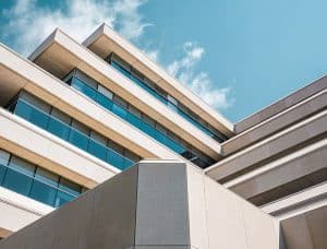 Modern multi-story apartment building with large glass windows, contemporary architecture, under a blue sky, representing professional property management services in Rochester.