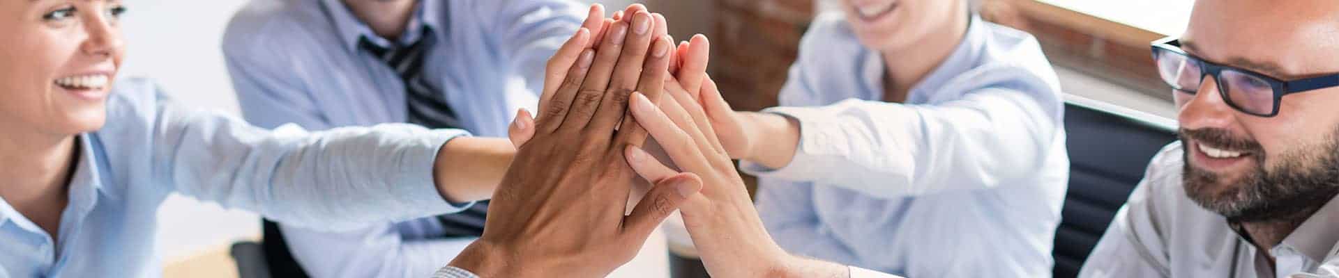 High five of diverse team members in a professional office, symbolizing teamwork and collaboration for Rochester Property Management Group.