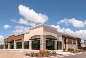 Modern commercial building with large glass windows and stone accents, showcasing professional property management services in Rochester.