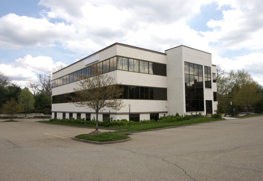 Modern commercial office building in Rochester with large glass windows, landscaped surroundings, and ample parking, representing professional property management services.