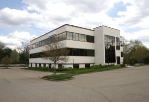 Modern commercial office building in Rochester with large glass windows, landscaped surroundings, and ample parking, representing professional property management services.