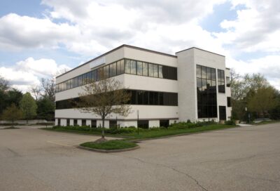 Modern commercial office building in Rochester with large glass windows, landscaped surroundings, and ample parking, representing professional property management services.