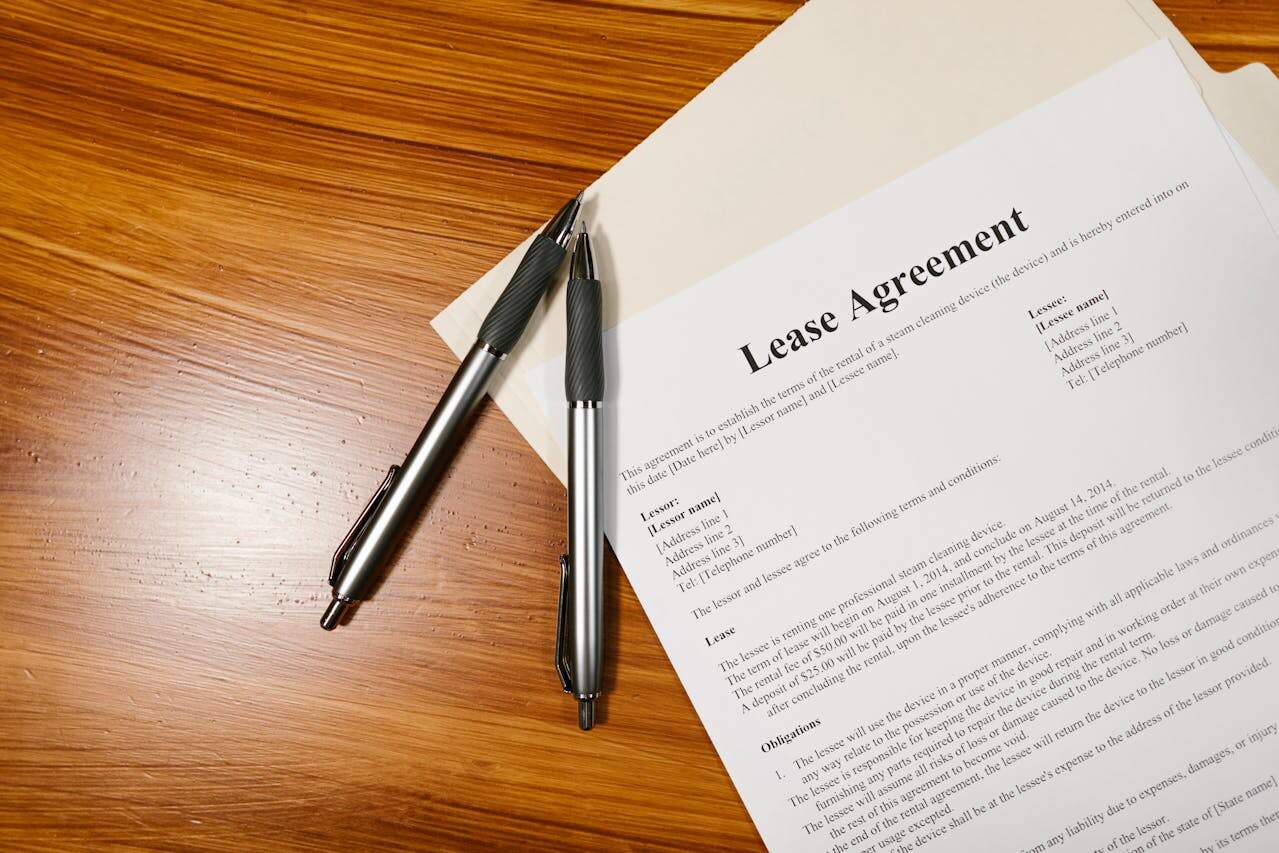 A lease agreement form on a wooden desk with two pens, illustrating rental contract documentation.