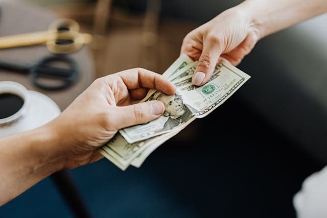 $20 bills being exchanged in a financial transaction, representing property management payments or rent collection at Rochester Property Management Group, Rochester NY.