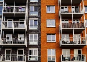 Modern apartment building with brick exterior, featuring multiple balconies and large windows, exemplifying Rochester Property Management Group's expert property management services in Rochester, NY.