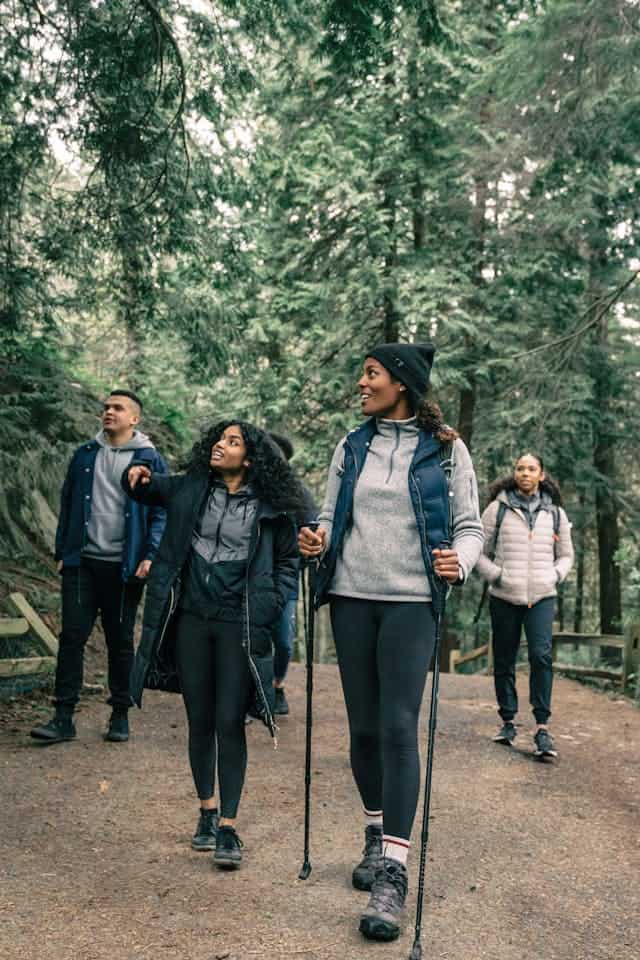Rochester Property Management Group, outdoor group of diverse young adults hiking in a lush green forest, promoting community engagement and outdoor activities in Rochester, NY.