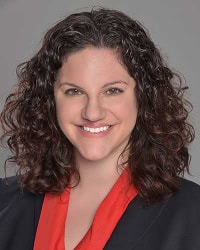 Professional woman with curly hair smiling, representing Rochester Property Management Group, expert in residential and commercial property management services in Rochester NY.