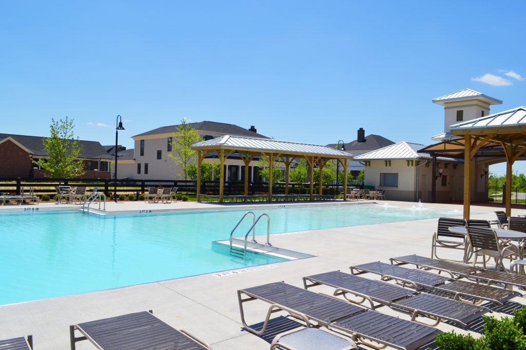 Modern outdoor swimming pool at Rochester Property Management Group community with sun loungers, shaded pavilions, and landscaped surroundings for residents’ leisure.