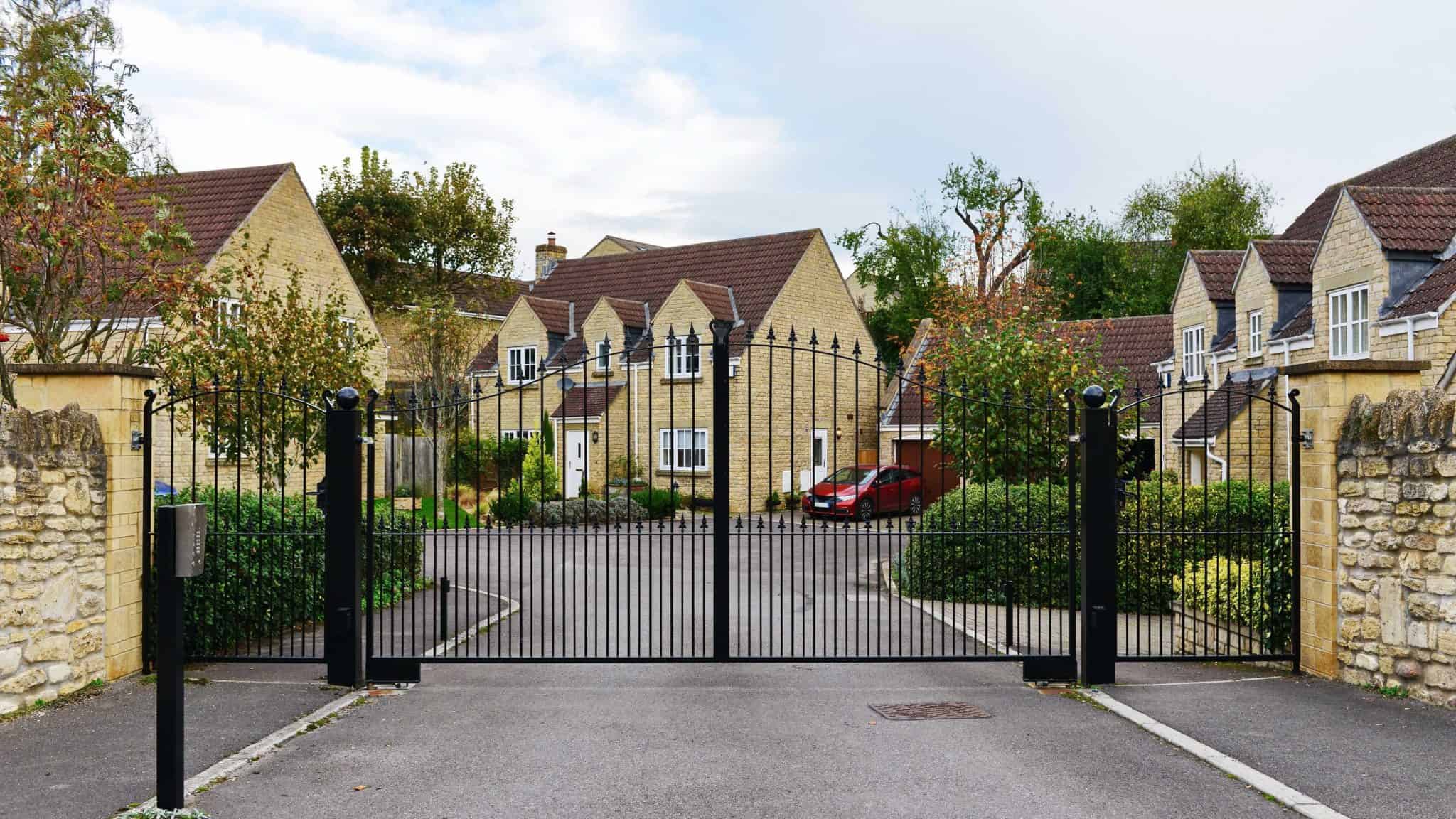 Gated community entrance to rental properties with well-maintained yellow brick houses and lush greenery, showcasing professional property management services by Rochester Property Management Group in Rochester.