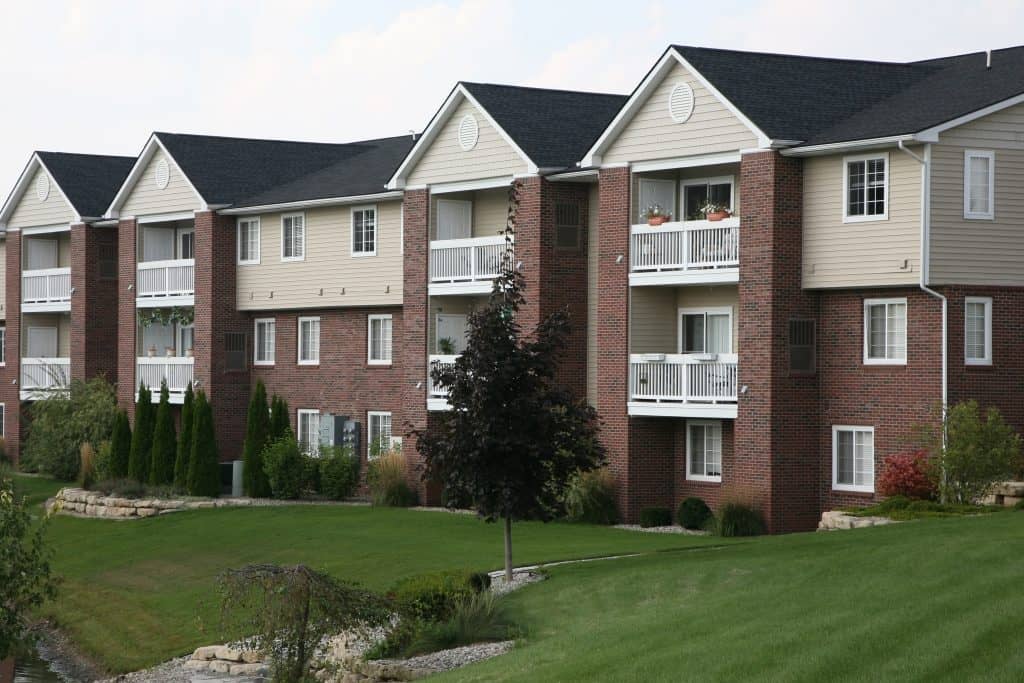 Modern multi-family residential apartment building with well-maintained landscaping and green lawns in Rochester, ideal for property management and rental investment.