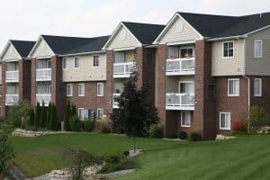 Modern multi-family residential apartment building with well-maintained landscaping and green lawns in Rochester, ideal for property management and rental investment.