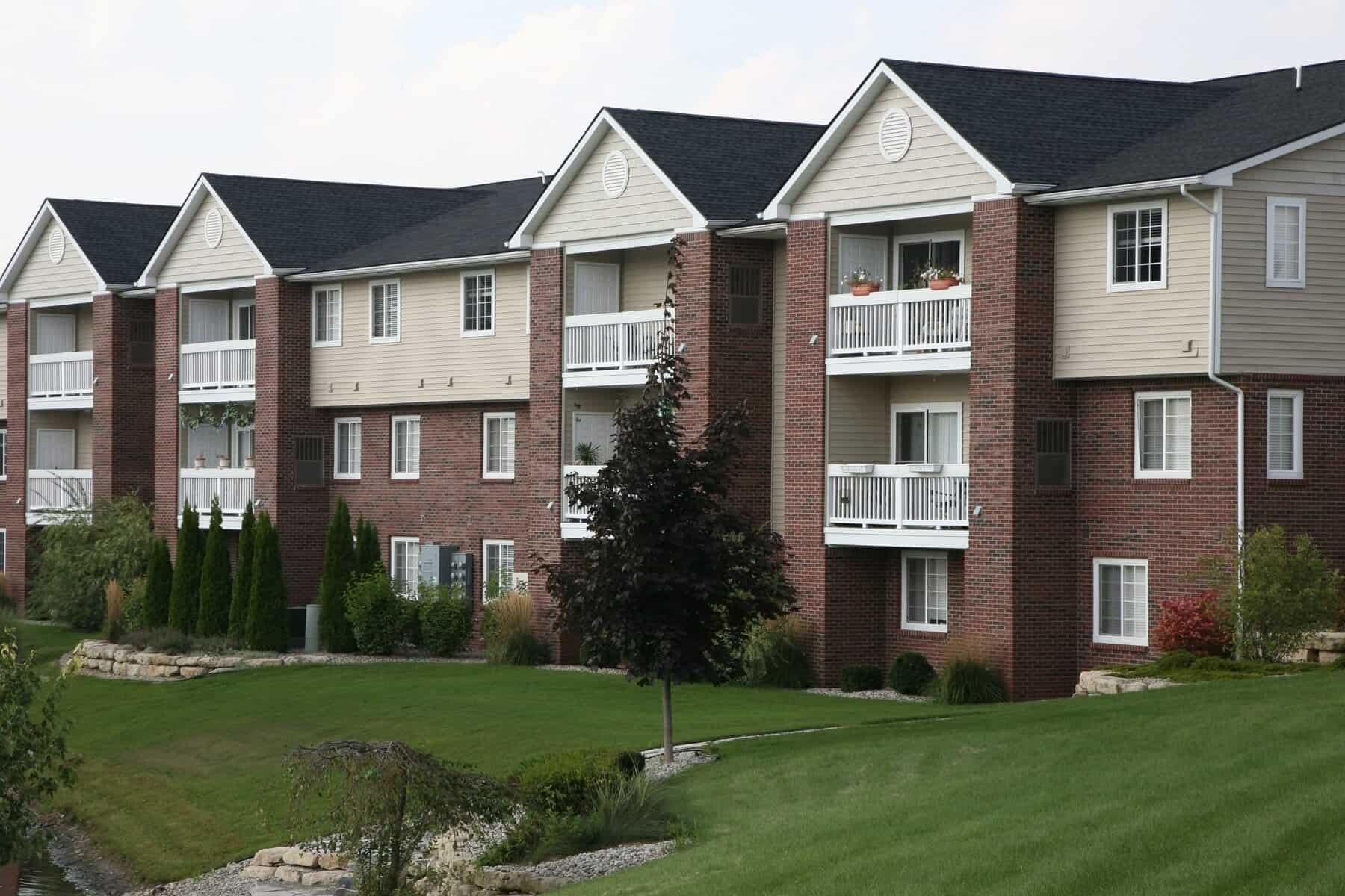 Modern multi-family residential apartment building with well-maintained landscaping and green lawns in Rochester, ideal for property management and rental investment.